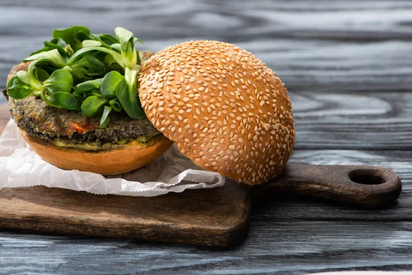 Hambúrguer vegan saboroso com microgreens servido na placa de corte na mesa de madeira — Fotografia de Stock