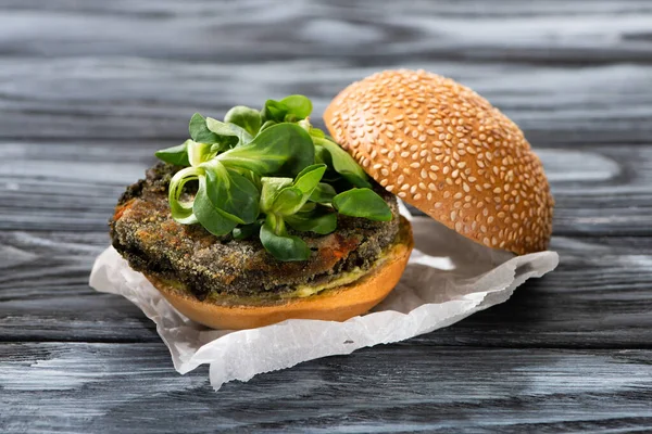 Tasty vegan burger with microgreens served on wooden table — Stock Photo