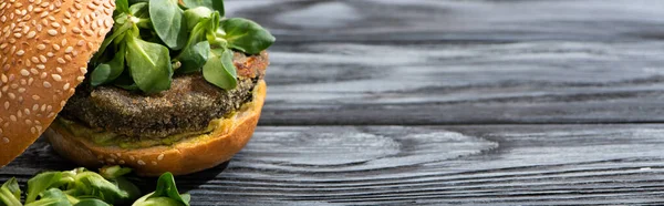 Sabrosa hamburguesa vegana con microgreens servidos en mesa de madera, cultivo panorámico - foto de stock