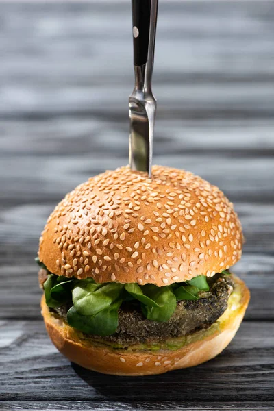 Hamburger végétalien savoureux avec microgreens et couteau sur table en bois — Photo de stock