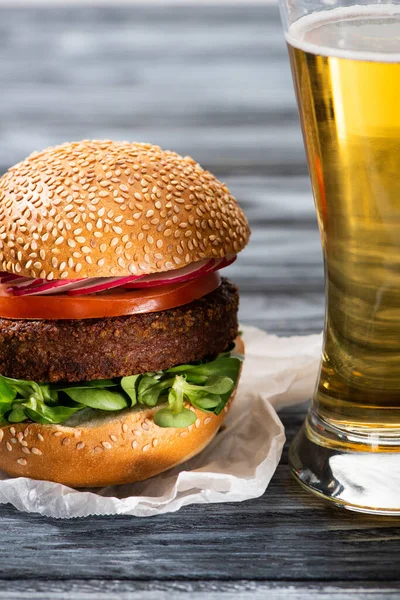 Tasty vegan burger with microgreens, radish and tomato served on wooden table with beer — Stock Photo