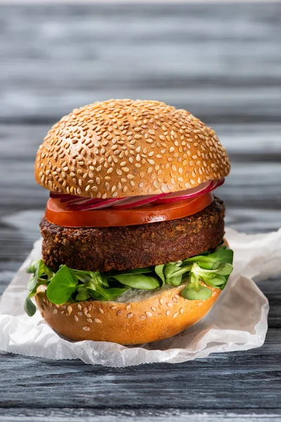 Tasty vegan burger with microgreens, radish and tomato served on wooden table — Stock Photo