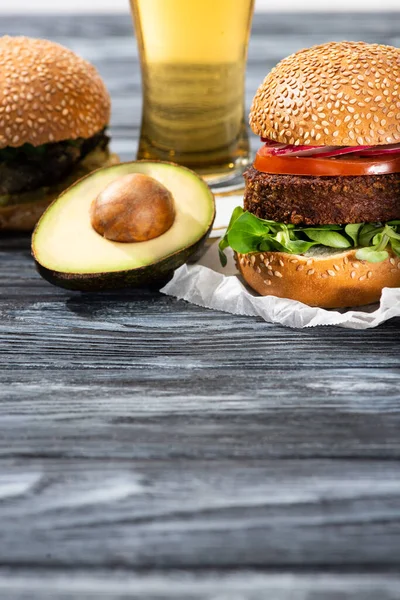 Sabrosas hamburguesas veganas servidas en mesa de madera con cerveza y aguacate - foto de stock