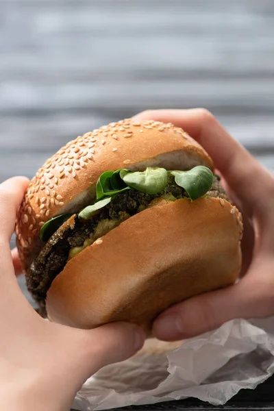 Cropped view of woman holding tasty vegan burger with microgreens — Stock Photo