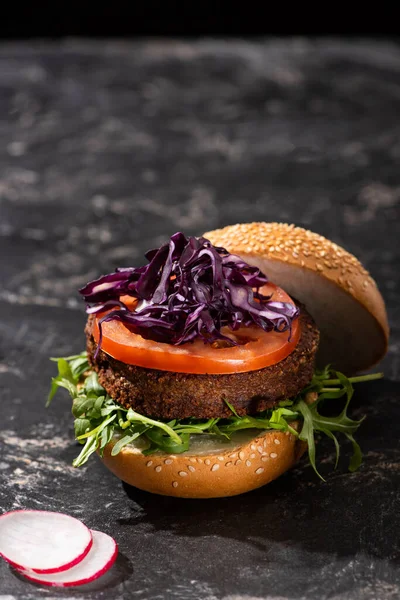 Tasty vegan burger with tomato, red cabbage and greens served on textured surface with radish — Stock Photo