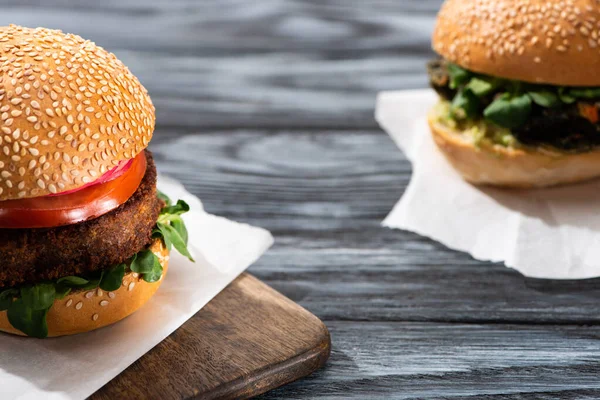 Enfoque selectivo de sabrosas hamburguesas veganas servidas en mesa de madera - foto de stock
