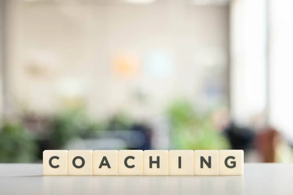 Cubos blancos con inscripción de coaching en el escritorio blanco - foto de stock