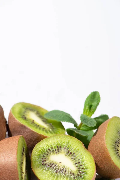 Foyer sélectif des moitiés de kiwis près des feuilles de menthe poivrée isolées sur du blanc — Photo de stock