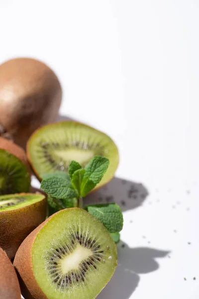 Enfoque selectivo de las mitades de kiwi fruta cerca de las hojas de menta en blanco - foto de stock