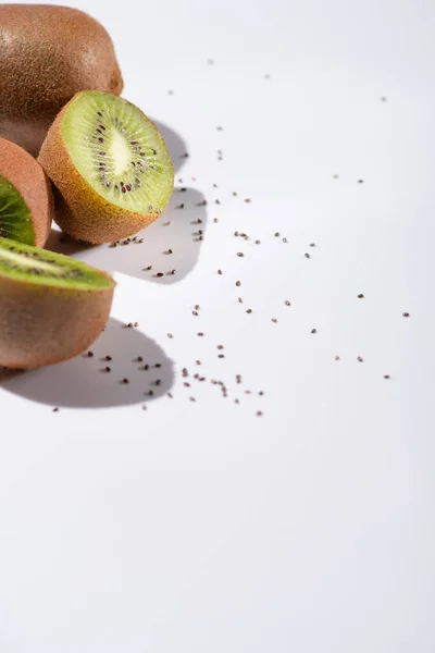 Foco seletivo de kiwi frutas metades perto de sementes pretas em branco — Fotografia de Stock