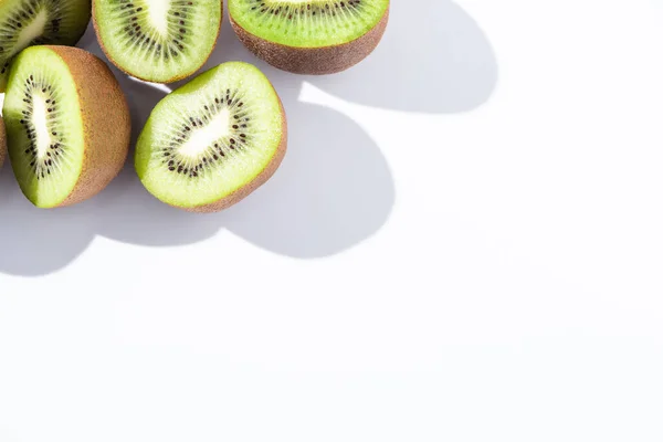 Vista superior de las mitades de kiwis frescos y maduros en blanco - foto de stock