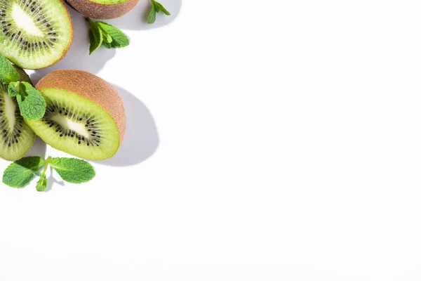 Vista superior de kiwi maduro metades de frutas perto de hortelã-pimenta em branco — Fotografia de Stock