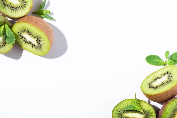 Vista dall'alto di metà di kiwi maturi vicino a menta piperita verde su bianco — Stock Photo