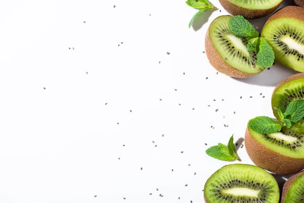 Top view of ripe kiwi fruit halves near peppermint and black seeds on white — Stock Photo