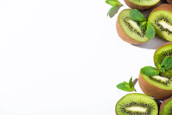 Vista superior de las mitades de kiwi fresco cerca de menta verde sobre blanco — Stock Photo