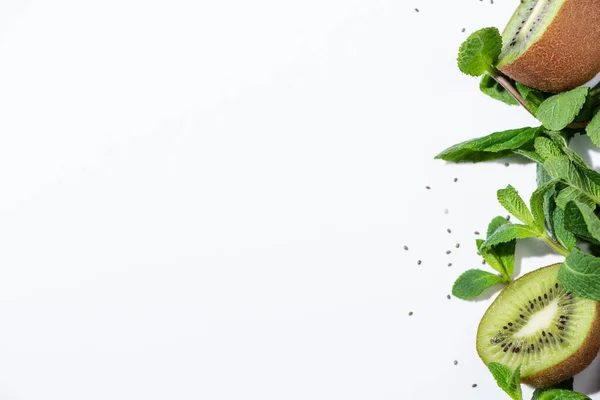 Vista dall'alto di gustosi kiwi vicino menta piperita verde e semi neri su bianco — Foto stock