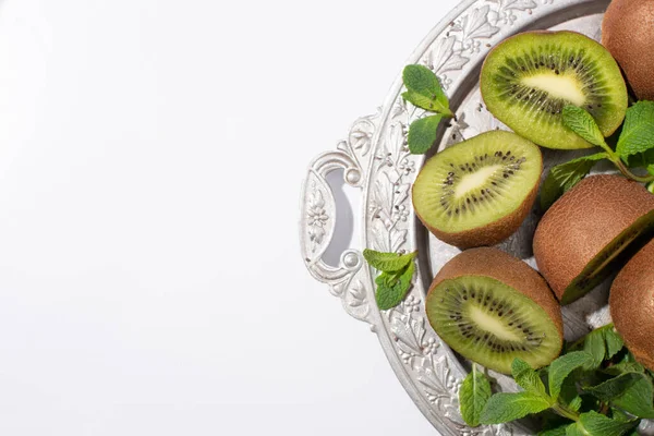 Top view of juicy kiwi fruits near green peppermint on silver plate isolated on white — Stock Photo