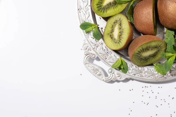 Vue de dessus des fruits juteux de kiwi près de menthe poivrée verte sur la plaque d'argent sur blanc — Photo de stock