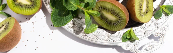 Horizontal concept of tasty kiwi fruits near fresh peppermint on silver plate on white — Stock Photo