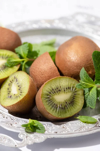 Selective focus of tasty kiwi fruits near fresh peppermint on plate — Stock Photo