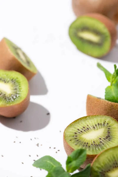 Messa a fuoco selettiva di kiwi vicino menta piperita biologica e semi neri su bianco — Foto stock