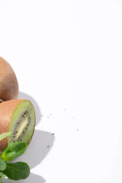 Selective focus of juicy kiwi fruits near peppermint and black seeds on white — Stock Photo