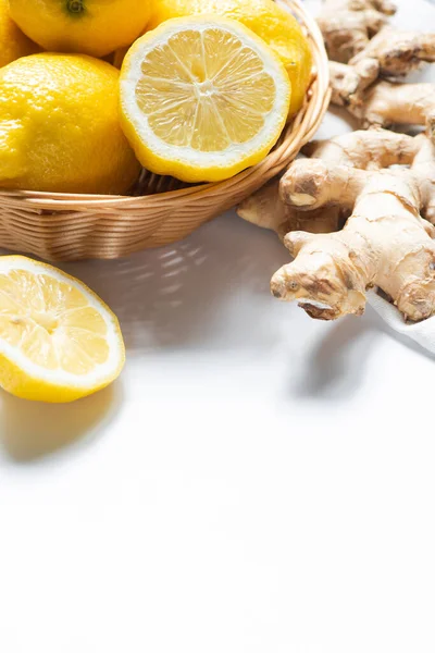 Close up view of basket of fresh lemons and ginger root on napkin on white background — Stock Photo