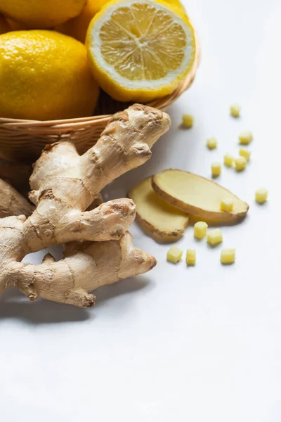 Close up view of basket of fresh lemons and ginger root on white background — Stock Photo