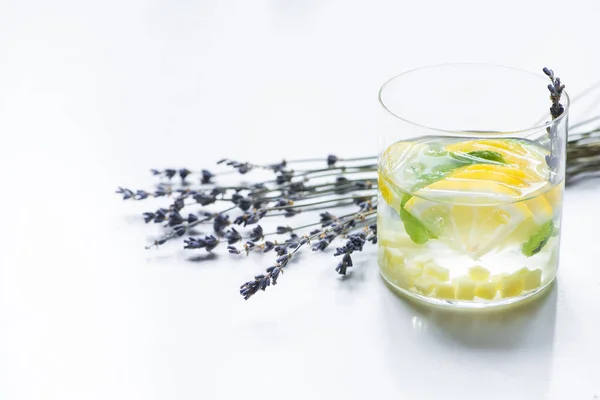 Limonada de jengibre fresca en vidrio con rama de menta y lavanda sobre fondo blanco - foto de stock