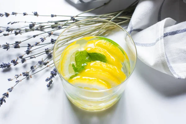 Limonade au gingembre frais en verre avec menthe près de la lavande et serviette sur fond blanc — Photo de stock