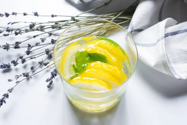 Fresh ginger lemonade in glass with mint near lavender and napkin on white background — Stock Photo