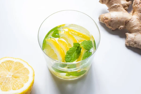 Fresh lemonade in glass near lemon and ginger root on white background — Stock Photo