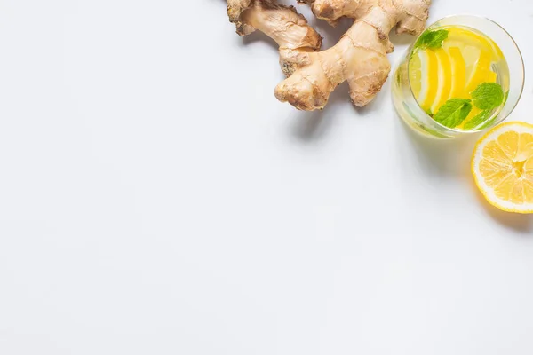 Vue de dessus de la limonade fraîche en verre près de citron et racine de gingembre sur fond blanc — Photo de stock