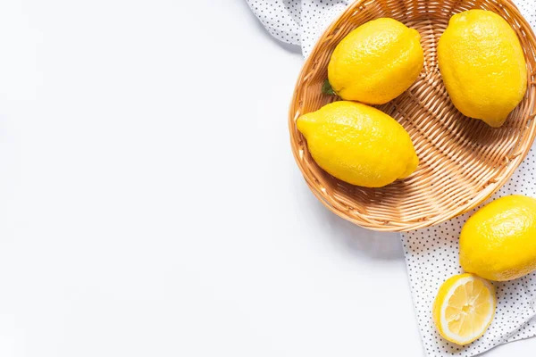 Top view of ripe lemons in wicker basket on white background with dotted napkin — Stock Photo