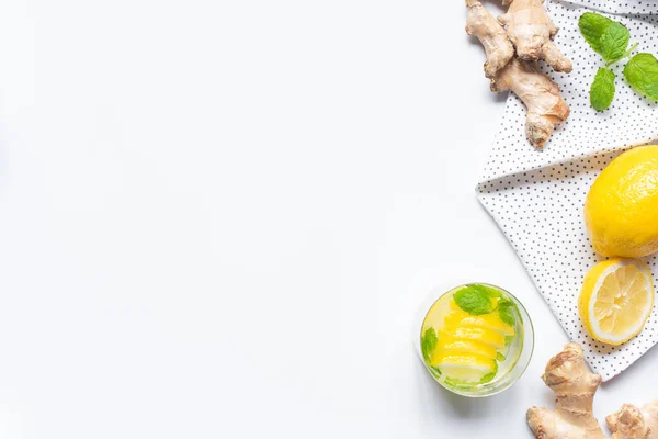 Vue du dessus de la limonade fraîche en verre près des citrons et de la racine de gingembre sur fond blanc avec serviette — Photo de stock