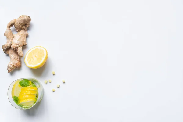 Vue de dessus de la limonade fraîche en verre près de citron et racine de gingembre sur fond blanc — Photo de stock