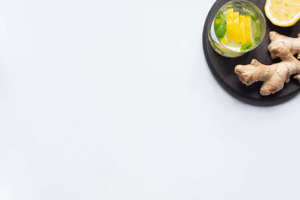 Vue du dessus de limonade fraîche en verre près de citrons et racine de gingembre sur panneau noir sur fond blanc — Photo de stock