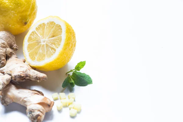 Raíz de jengibre fresca, limón y menta sobre fondo blanco - foto de stock