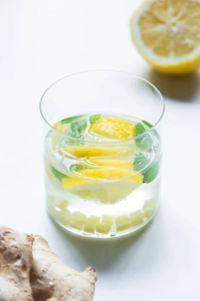 Foyer sélectif de limonade fraîche dans le verre près de citron et racine de gingembre sur fond blanc — Photo de stock