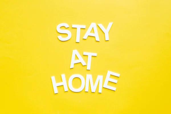 Vue de dessus du lettrage de séjour à la maison sur la surface jaune — Photo de stock