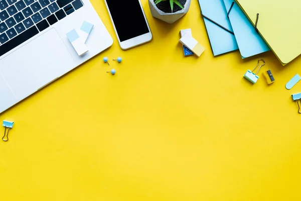 Ansicht digitaler Geräte in Werks- und Schreibwarennähe auf gelbem Hintergrund — Stockfoto