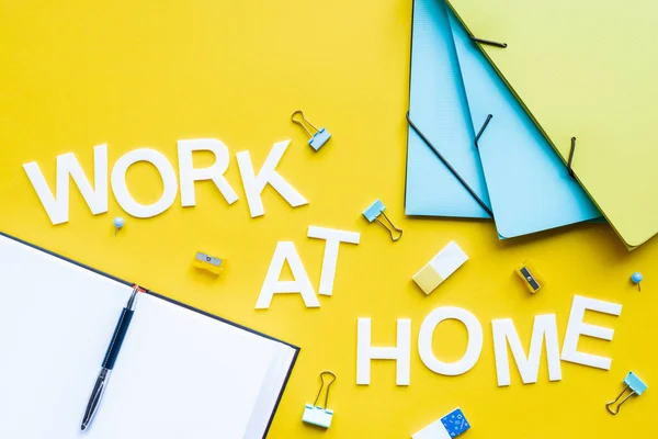 Vista dall'alto del lavoro in casa lettering e cancelleria con libro aperto su superficie gialla — Foto stock