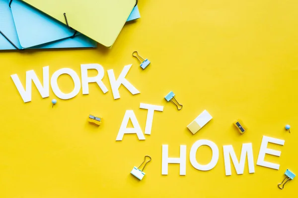 Ansicht von Papiermappen, Arbeit zu Hause Schriftzug und Schreibwaren auf gelber Oberfläche — Stockfoto