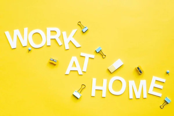 Vista superior del trabajo en casa con rotuladores de lápiz, clips de encuadernación y goma de borrar en la superficie amarilla - foto de stock