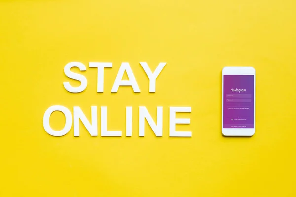 KYIV, UKRAINE - APRIL 8, 2020: Top view of stay online lettering and smartphone with instagram app on yellow surface — стокове фото