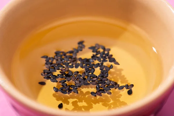 Nahaufnahme von Öl mit schwarzem Sesam in Schüssel — Stockfoto