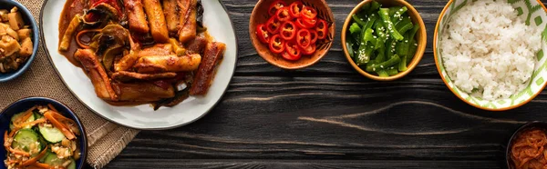 Horizontal image of korean traditional and spicy dishes near chopsticks and cotton napkin on wooden surface — Stock Photo