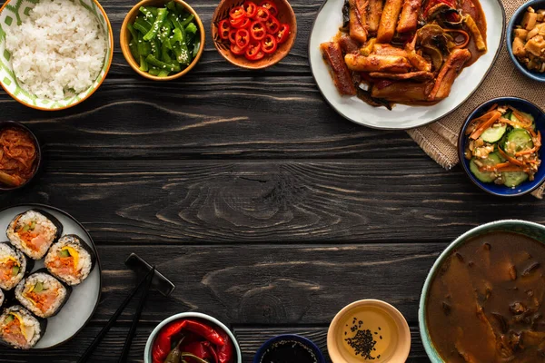 Vue de dessus des plats traditionnels coréens et épicés près des baguettes et de la serviette en coton sur la surface en bois — Photo de stock