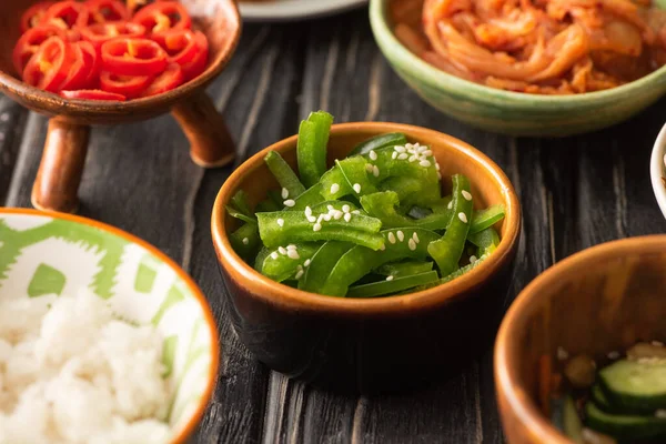 Selective focus of green bell peppers and red chili peppers near korean kimchi and rice — Stock Photo