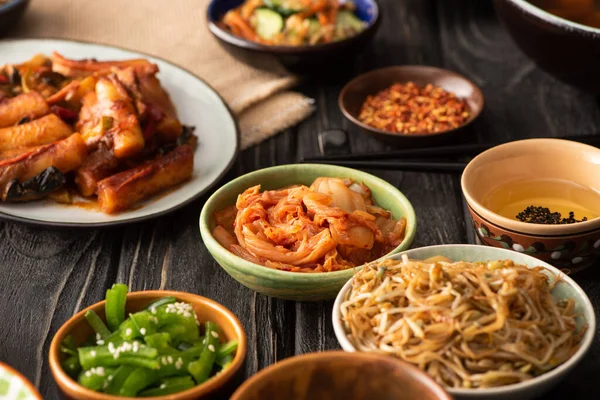 Selective focus of spicy kimchi near topokki and korean side dishes — Stock Photo